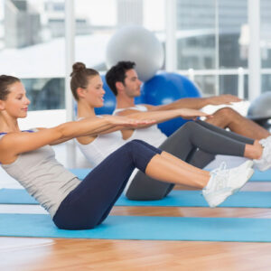 Group exercising with seated abdominal crunches on mats.