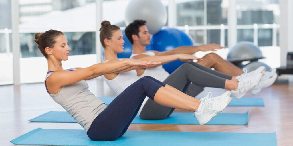 Group exercising with seated abdominal crunches on mats.